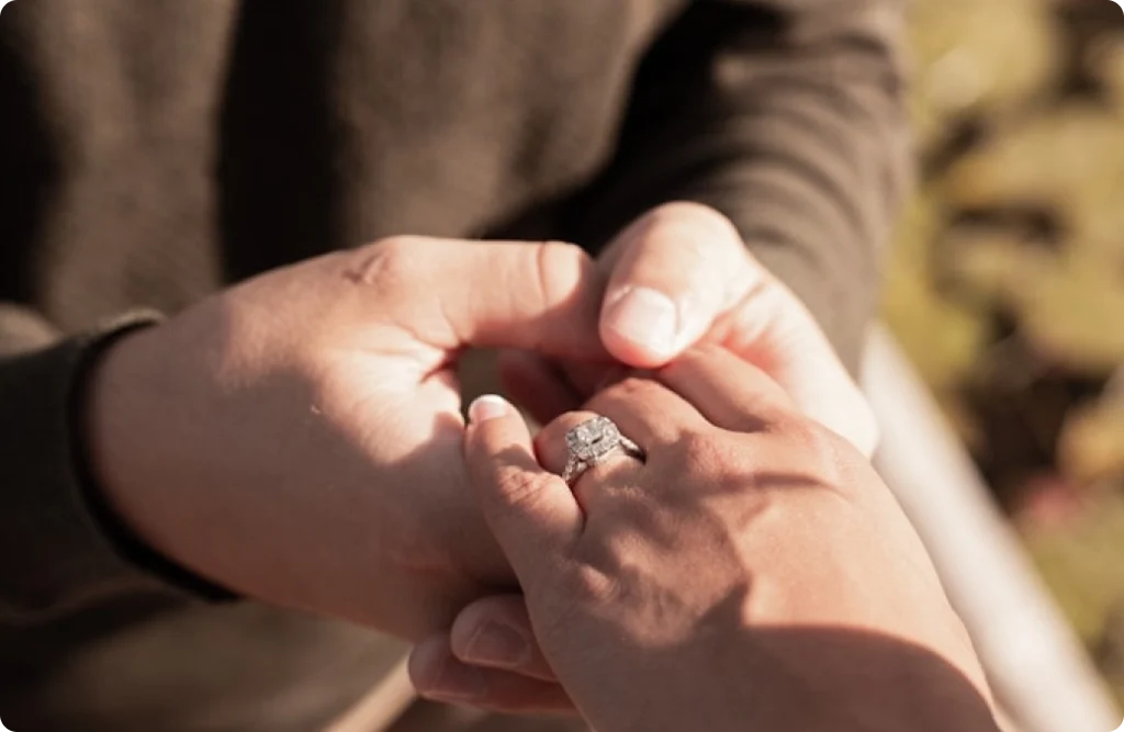 Photo des mains d'un homme qui tient la main d'une femme avec un solitaire au doigt pour une demande en mariage
