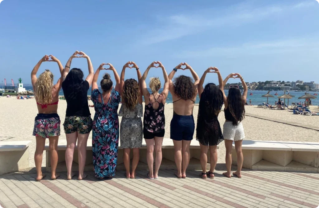 Photo de 8 filles de dos lors de la célébration d"un EVJF qui font des coeurs avec leurs mains