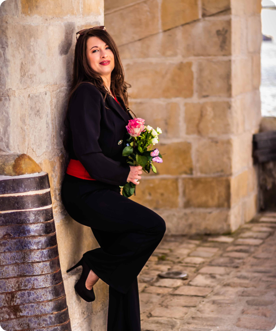 Photo de Aurélie Costa adossée à un mur avec un bouquet de marié à la main