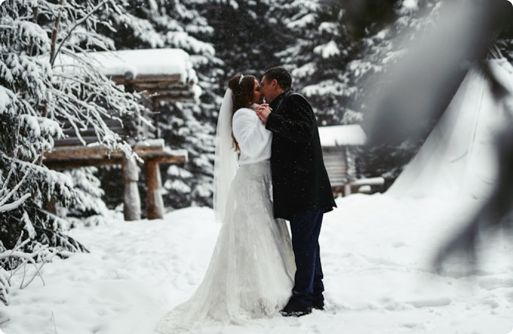 Photo d'un couple de jeunes mariés en tenue de mariage qui s'embrassent dans la neige pour un mariage d'hiver