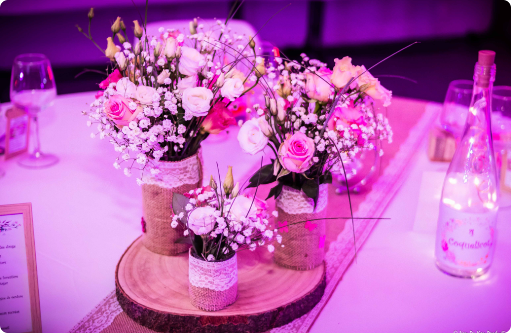 Photo d'une table de mariage dressée dans les ton rose avec bouquets de fleurs et vaiselle
